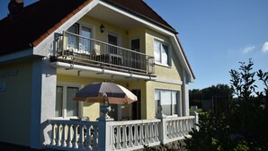 Une maison à deux étages dotée d’un balcon, d’une fenêtre avec un store blanc et de fondations en pierre.