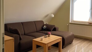 Un salon moderne avec un canapé d’angle marron, une table basse en bois et un lampadaire.