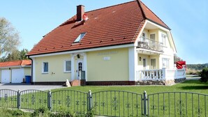 Una casa de dos pisos con techo de tejas rojas, un balcón en el segundo piso y un letrero que dice 'Haus zum Strand'.