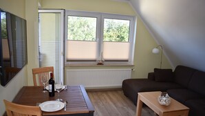 Un comedor con una mesa preparada para dos, una ventana con persianas, un sofá y una lámpara.