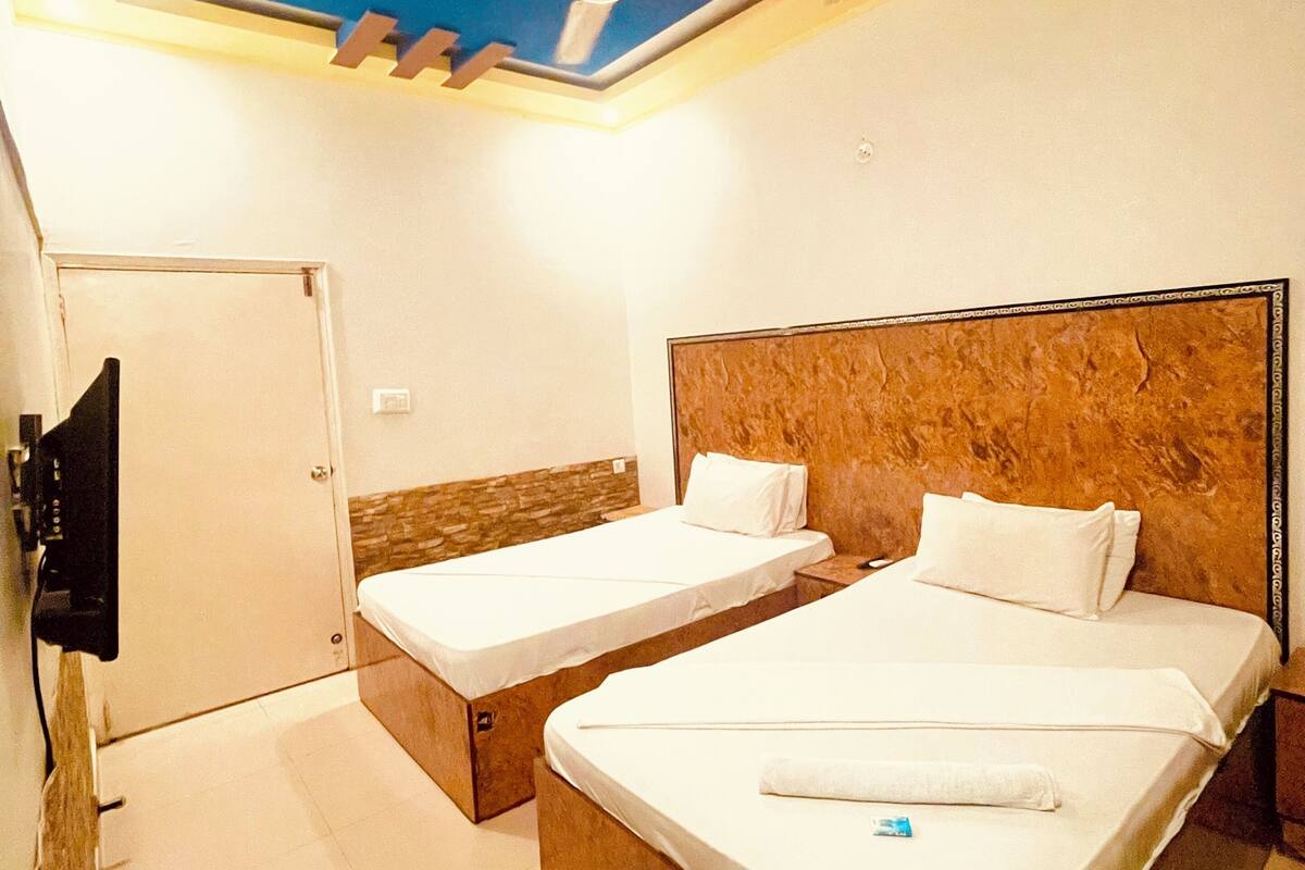 A hotel room with two beds, a ceiling fan, a TV, and a small seating area.