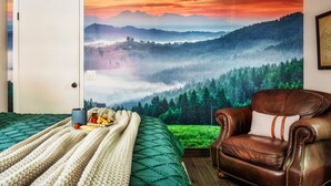 Un dormitorio con una cama grande, un sillón de cuero y un mural decorativo con un paisaje.