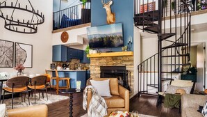 Una sala de estar moderna con chimenea, sofás de cuero, un comedor y una cocina al fondo.