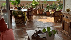 Une terrasse avec vue sur l’océan, comprenant une table, des chaises et des plantes en pot.