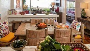 Un vaste espace de vie comprenant une table à manger, des meubles en osier et une vue sur l’extérieur.