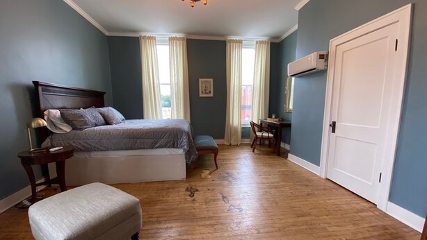 A bedroom with a bed, bedside table, chair, and a desk with a chair.