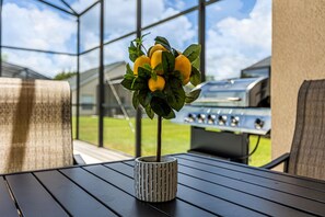 A potted lemon tree on a patio table with a grill in the background. - Disney Area 4BR Home with Heated Private Pool (Kissimmee)
