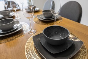 A dining table set with black bowls and plates, surrounded by chairs. - Disney Area 4BR Home with Heated Private Pool (Kissimmee)