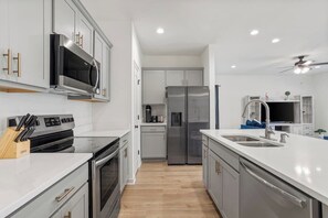 A modern kitchen with stainless steel appliances, white cabinetry, and a wooden countertop.