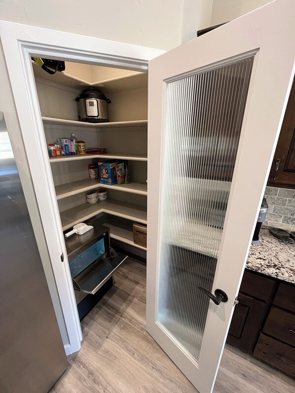 A kitchen with a built-in pantry, a microwave, and a coffee maker on the shelves.