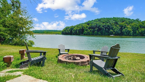 Vista del lago con una fogata y sillas Adirondack.
