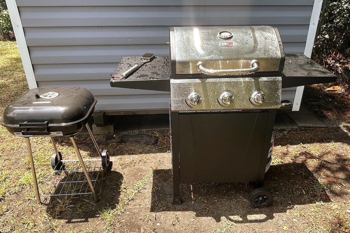 Ein tragbarer Grill mit Seitenbrenner und Staurraum, aufgebaut im Freien.