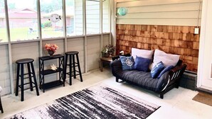 Uma sala de estar aconchegante com sofá de madeira, uma mesa de centro preta e dois bancos altos pretos.