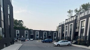 A street view with modern buildings, parked cars, and a clear sky. - Cozy 2-Bedroom Condo with Parking in Niagara Falls (Niagara Falls)