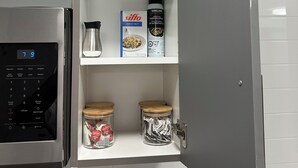 A kitchen with a built-in microwave, a coffee maker, and two spice jars on the shelves. - Cozy 2-Bedroom Condo with Parking in Niagara Falls (Niagara Falls)