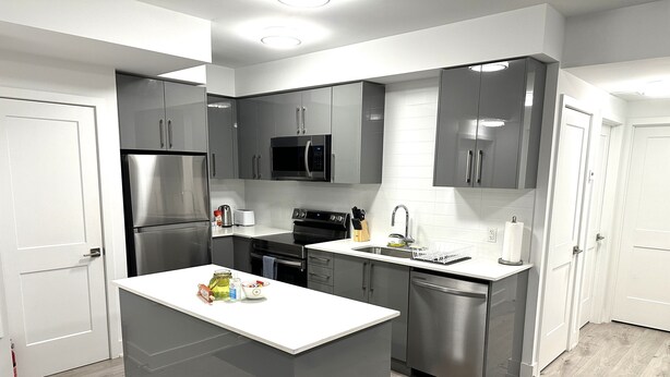 A modern kitchen with stainless steel appliances, a white countertop, and grey cabinetry. - Cozy 2-Bedroom Condo with Parking in Niagara Falls (Niagara Falls)