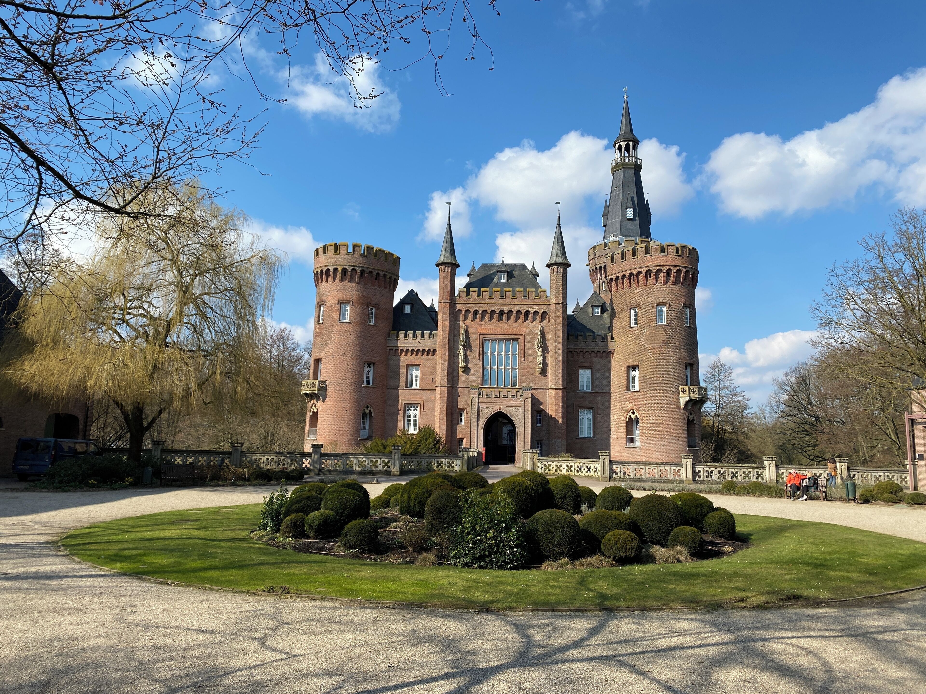 Um castelo grande e histórico, com várias torres e um jardim bem cuidado na frente.