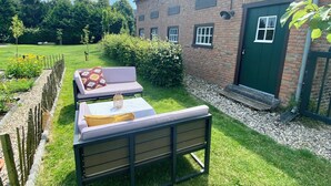 A grassy outdoor area with a bench and a table set up for outdoor dining.