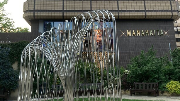 Un edificio moderno con facciata in vetro e la scritta "MANAHATTA" sul lato.