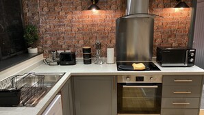 Una cucina moderna con parete in mattoni, elettrodomestici in acciaio inossidabile e forno integrato.