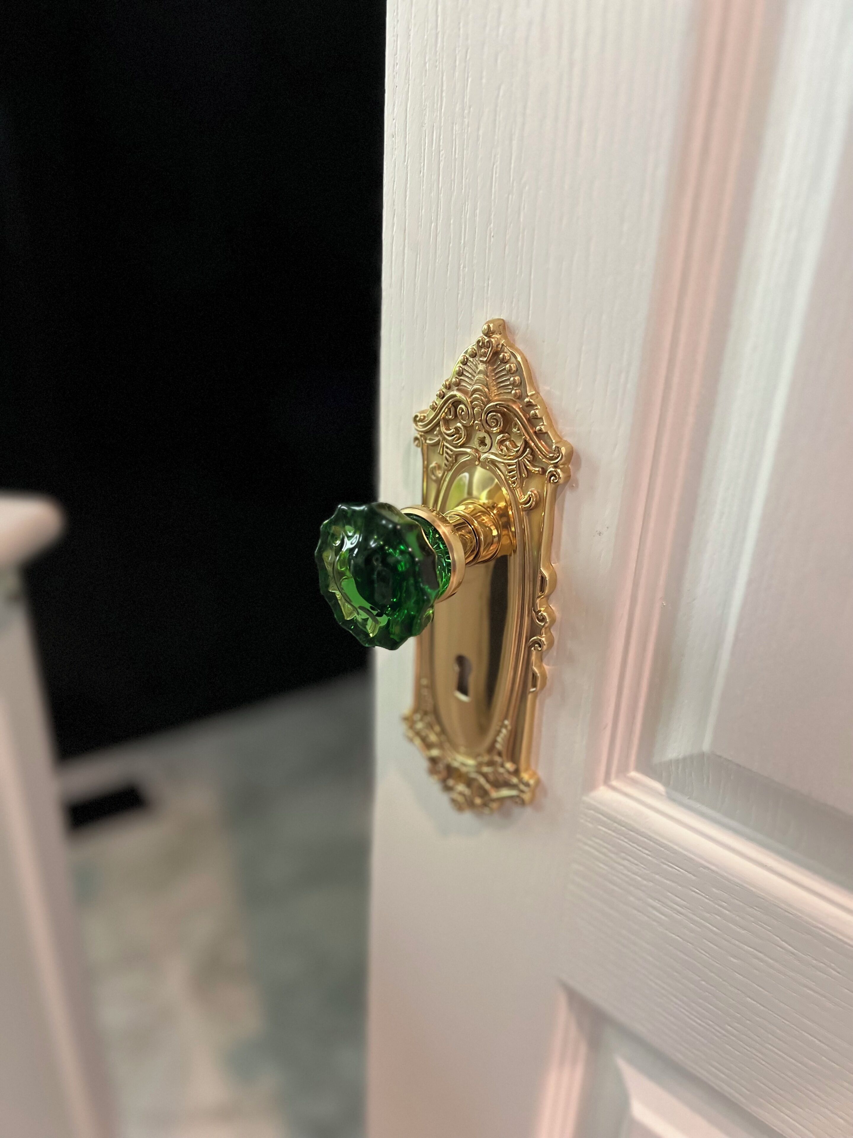 A door with an ornate golden handle and a green glass knob.