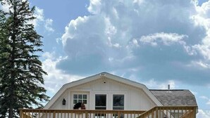 Une maison à deux étages dotée d’une terrasse en bois et d’un escalier menant à l’étage supérieur.