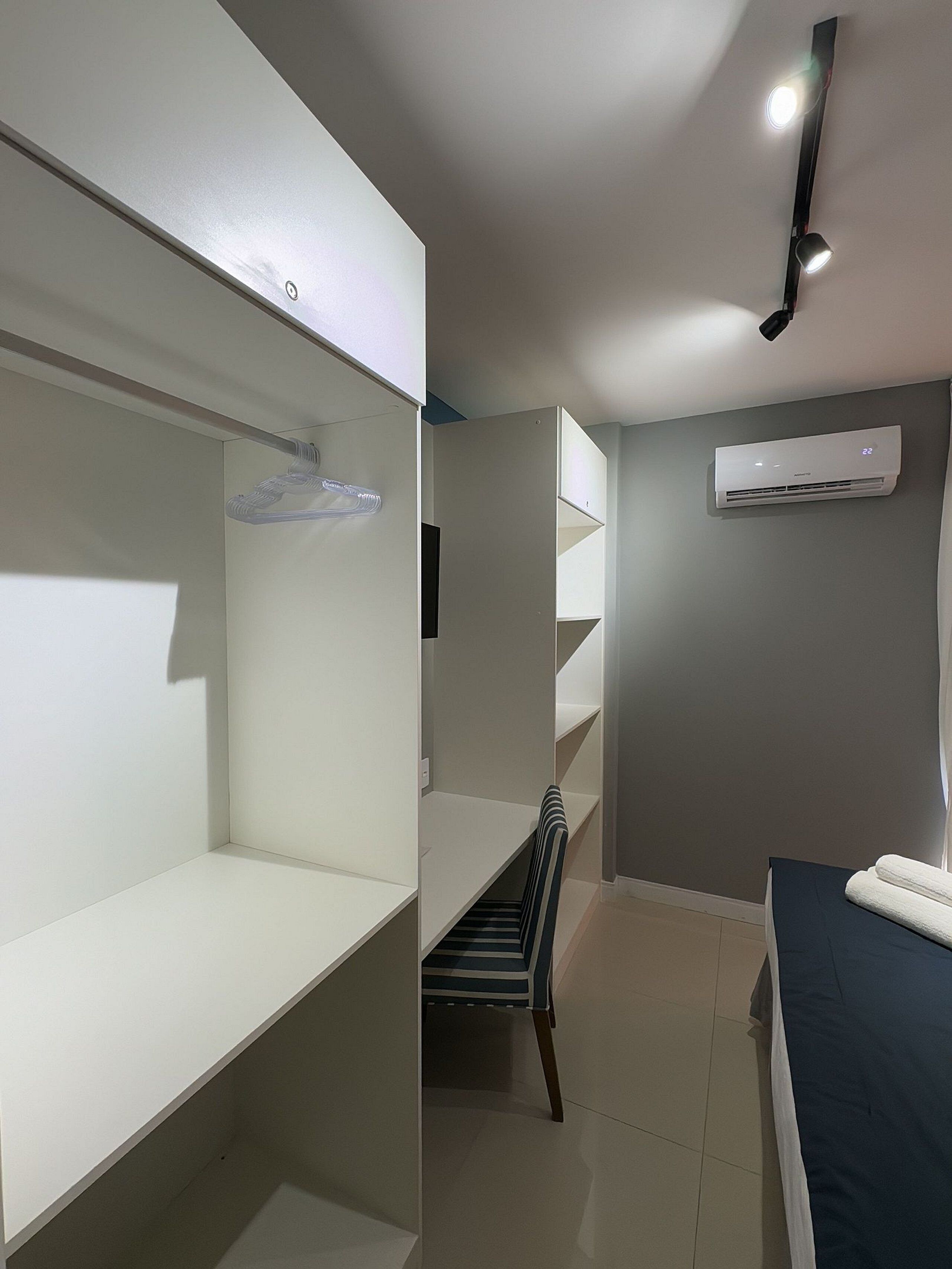 A room with bunk beds, a desk, a chair, and an air conditioning unit.