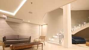 A modern living room with a sofa, chair, coffee table, and staircase. - hihome - Royale (Cabo Frio)