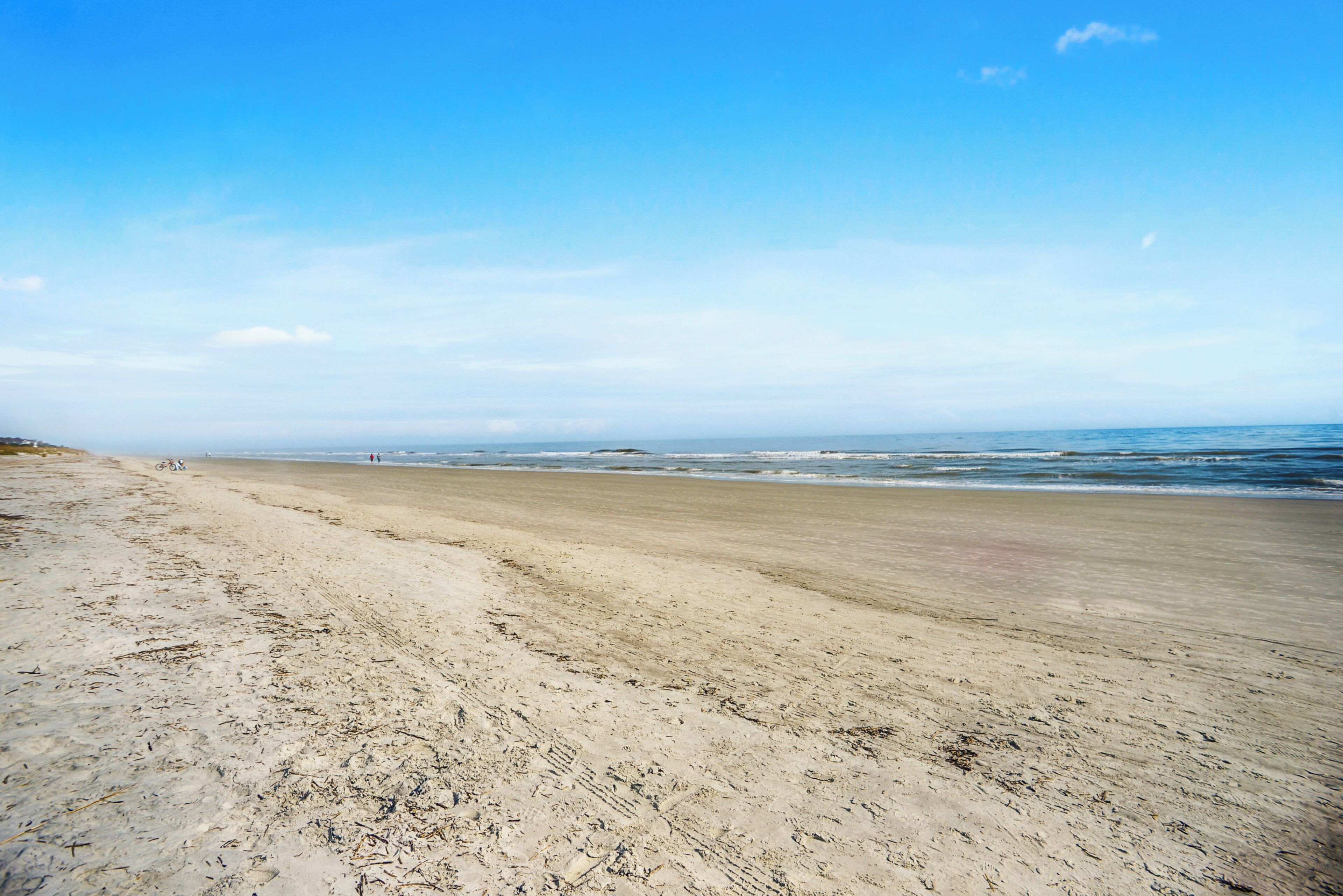 Une vaste plage de sable fin, avec des vagues douces et un ciel bleu clair.