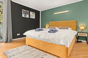 A bedroom with a bed, a nightstand, a lamp, and a window with curtains.