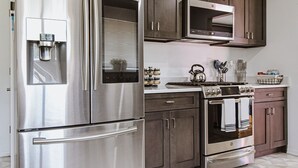 A modern kitchen with stainless steel appliances, dark wooden cabinets, and a geometric patterned floor. - 5BD Cozy, SouthGlenn Gem, Yard, Games, Shops, close to Downtown Littleton&Denver (Centennial)