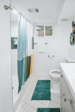 A small, white bathroom with a shower curtain, a toilet, and a sink. - 5BD Cozy, SouthGlenn Gem, Yard, Games, Shops, close to Downtown Littleton&Denver (Centennial)