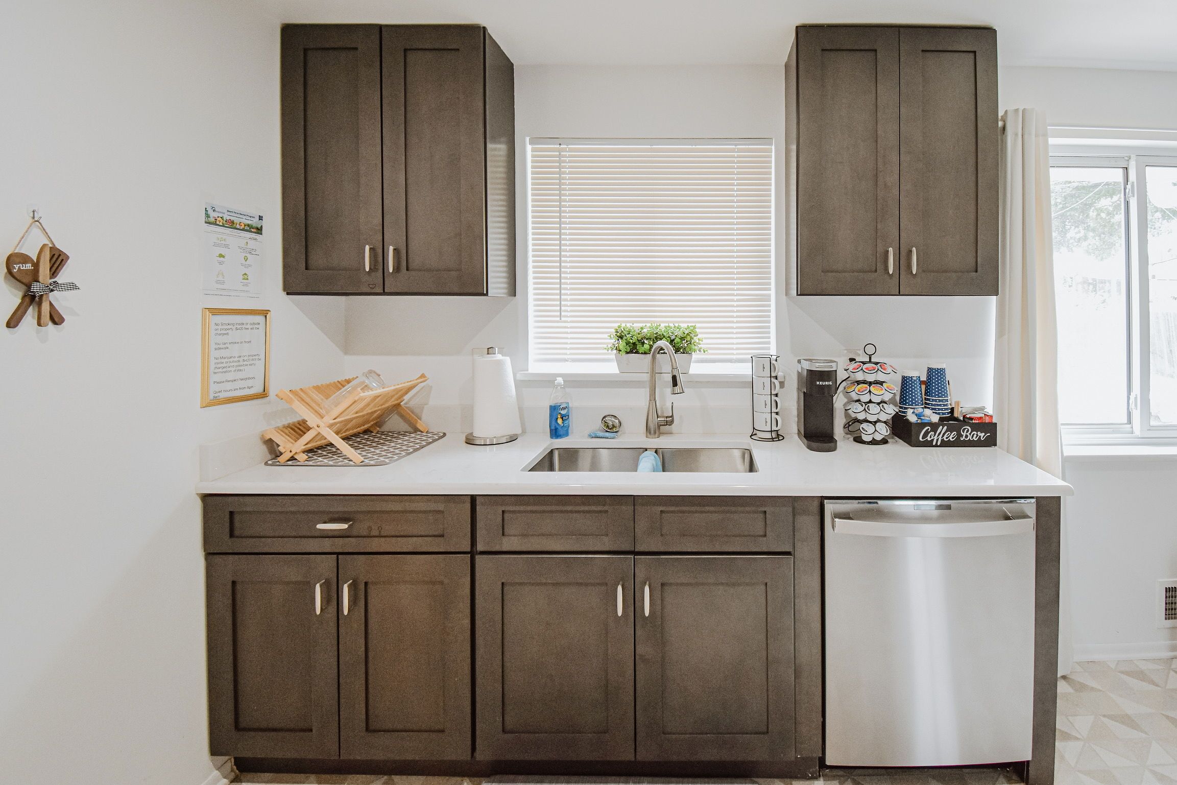 A modern kitchen with dark brown cabinets, a stainless steel dishwasher, and a white countertop.