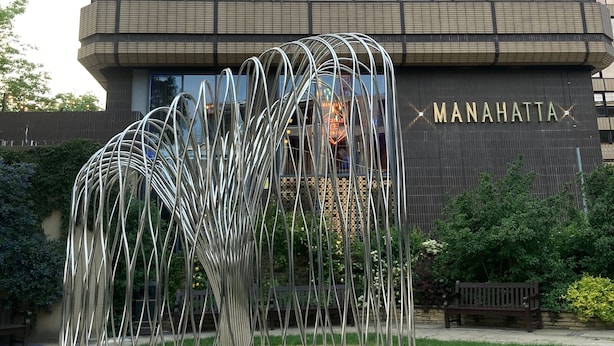 Ein modernes Gebäude mit Glasfassade und der Aufschrift "MANAHATTA" an der Seite.