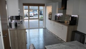 A modern kitchen with a marble countertop, stainless steel appliances, and a view of parked cars outside.