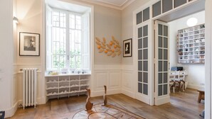 A spacious room with a large window, built-in shoe shelves, and a decorative wall piece. - Villa Michelangelo, your home in the heart of the eternal city (Roma)