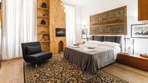 A modern bedroom with a large bed, a wooden wall unit, a black sofa, and a patterned rug. - Villa Michelangelo, your home in the heart of the eternal city (Roma)