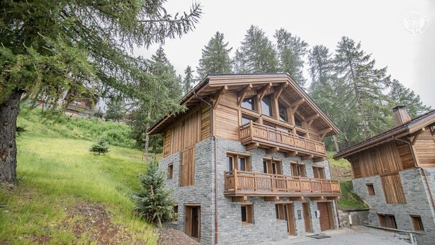 A chalet-style building with a stone facade, wooden balconies, and a hilly backdrop. - MONT ROSE - LA PLAGNE TARENTAISE (LA PLAGNE TARENTAISE)