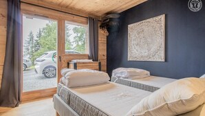 A room with two beds, a wooden ceiling, a large window, and a wall-mounted artwork. - MONT ROSE - LA PLAGNE TARENTAISE (LA PLAGNE TARENTAISE)