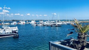 Ein Yachthafen mit mehreren vertäuten Booten, ruhigem Wasser und blauem Himmel.