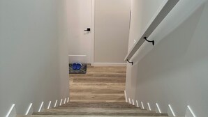 A modern staircase with wooden steps and white walls. - 2 Bedroom 1.5 Bathroom Brand New, Tranquil Suite: Your Gateway to Rockies & City (Calgary)
