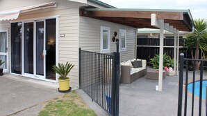 A house with a covered patio, sliding glass doors, and a pool area. - The Pool House Bed & Breakfast - 50 sq Kitchenette Studio - Near Marine Parade (Napier)