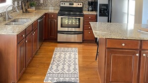 A modern kitchen with wooden cabinets, stainless steel appliances, a granite countertop, and a black ceiling. - 2 Bed/2 Bath Home in Andover area. Premier Host with 250+ 5-Star Reviews! (Lexington)