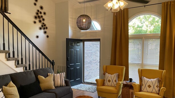 A spacious living room with a dark gray sofa, two yellow armchairs, a black coffee table, and a ceiling fan. - 2 Bed/2 Bath Home in Andover area. Premier Host with 250+ 5-Star Reviews! (Lexington)