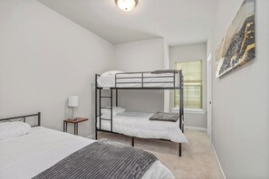 Ein Schlafzimmer mit Etagenbetten, einem Nachttisch mit Lampe und einem Fenster mit Jalousien.