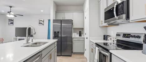 A modern kitchen with stainless steel appliances, a central island, and white cabinetry.