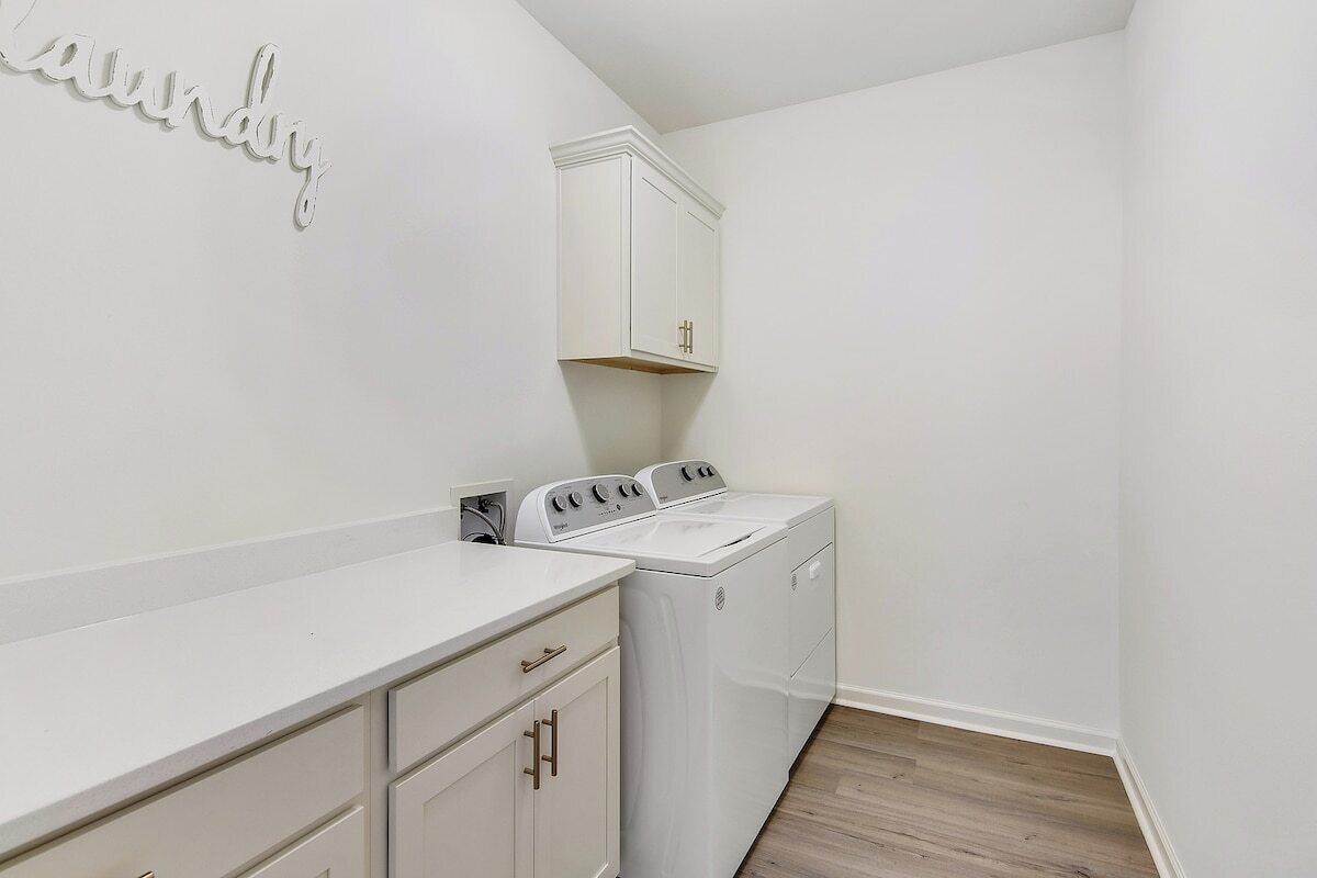 A laundry room with a white countertop, a washing machine, and a dryer.