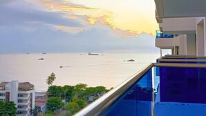 A balcony with a view of the sea and ships, overlooking a hotel with a white facade and a thatched roof. - Amazing Apartment in Beach Club - Samaria! (Gaira)