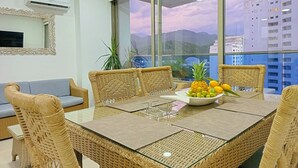 A dining area with wicker furniture, a glass table, and a bowl of fruit. - Amazing Apartment in Beach Club - Samaria! (Gaira)