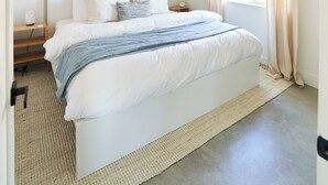 A bedroom with a large bed, a hanging light fixture, a window with curtains, and a wall-mounted artwork. - Private Guest House with Full Kitchen, 30 minutes to L.A. & Beach (Thousand Oaks)